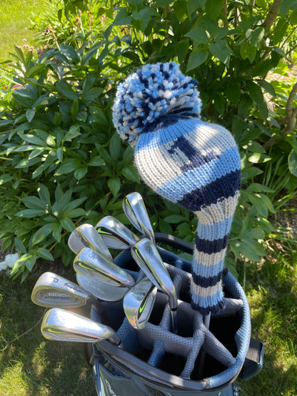 A set of golf clubs with a knit driver cover that has a 1 on it and blue and grey stripes