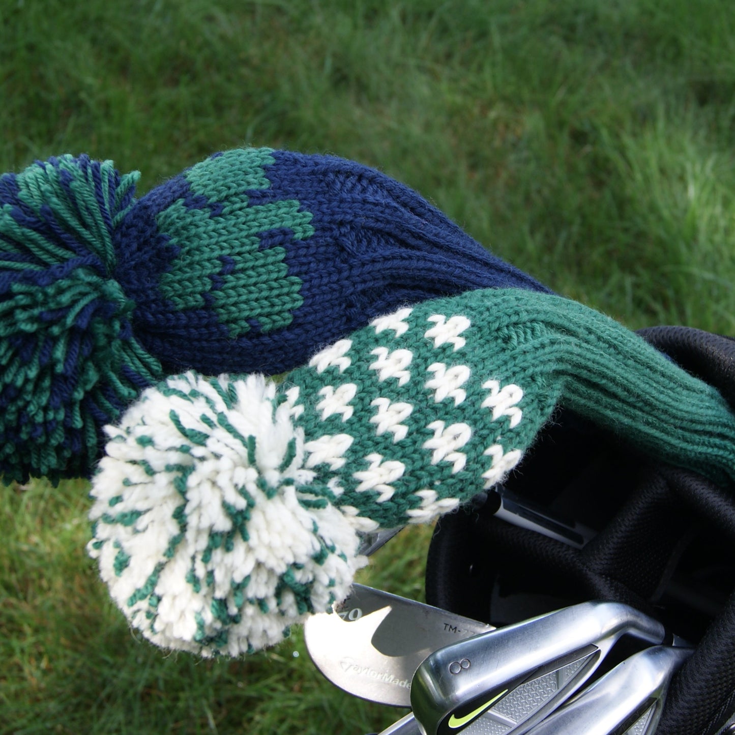 Golf club with green and blue fuzzy covers on a grassy background