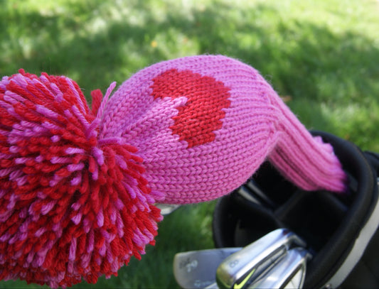 Pink and red knitted driver cover with heart design on a golf club