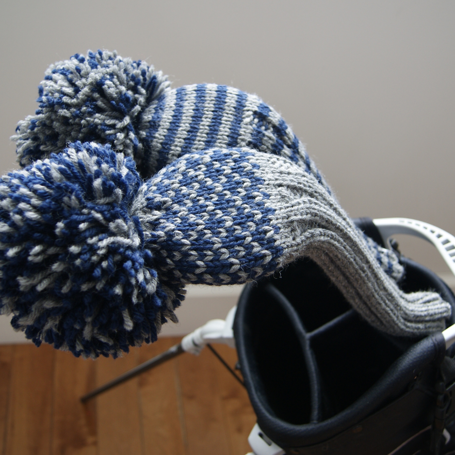 Knitted blue and gray striped golf club headcover against a neutral background
