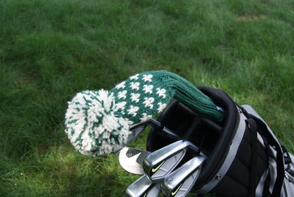 Golf club head cover with white and green pattern on a golf bag against a grass background